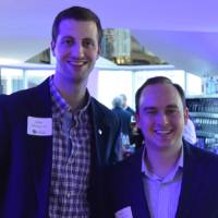 Two alumnus smile for a photo together